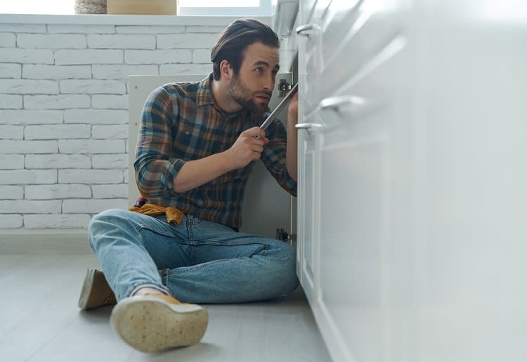Man on the floor fixing sink with a wrench