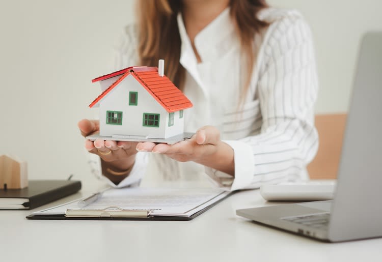A woman hold a model of a house at her desk