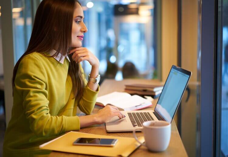 How Much Does It Cost to Build a Website in 2025? a woman sitting at a table using a laptop computer