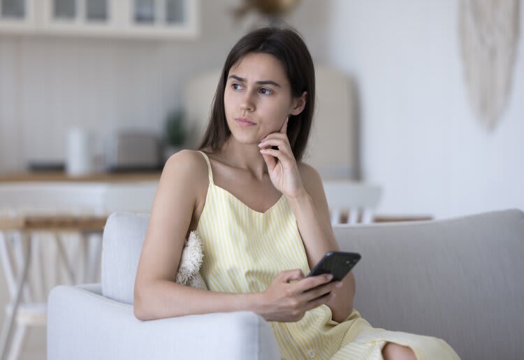 a woman sitting on a couch holding a cell phone